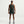 Man wearing a dark green tank top and shorts on a light gray background