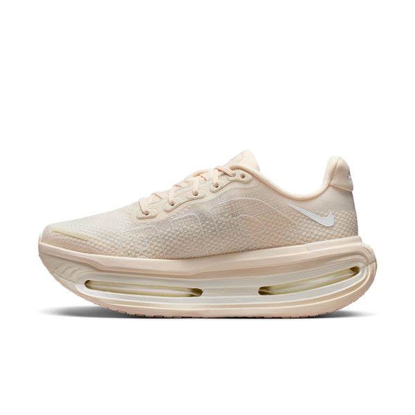 Medial side of a beige running shoe with a white sole on a white background.