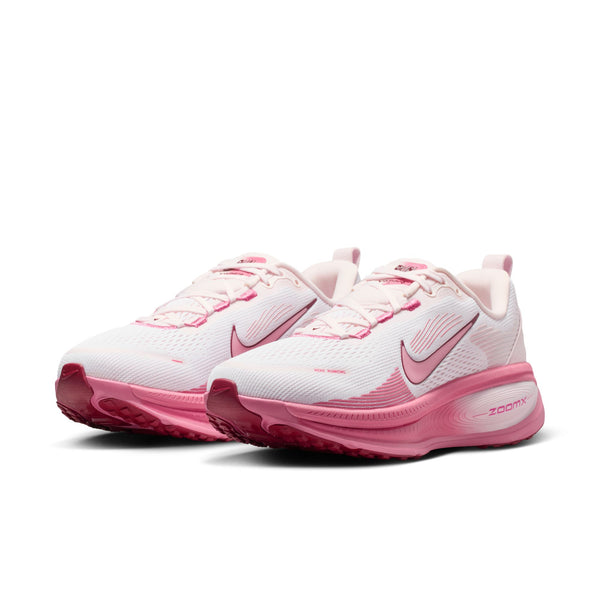 A pink of womens white and pinkish running shoes with Nike logo on a white background.