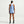 A woman shown from the back wearing a light blue sleeveless athletic tank top and matching shorts with dark blue trim, standing against a clean off-white studio background.