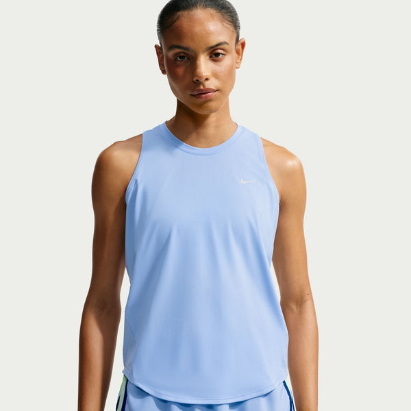 A woman wearing a light blue sleeveless athletic tank top with a small white Nike swoosh on the chest, photographed against a plain light gray studio background.