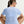 Woman wearing a light blue athletic shirt sitting on the ground with a neutral background