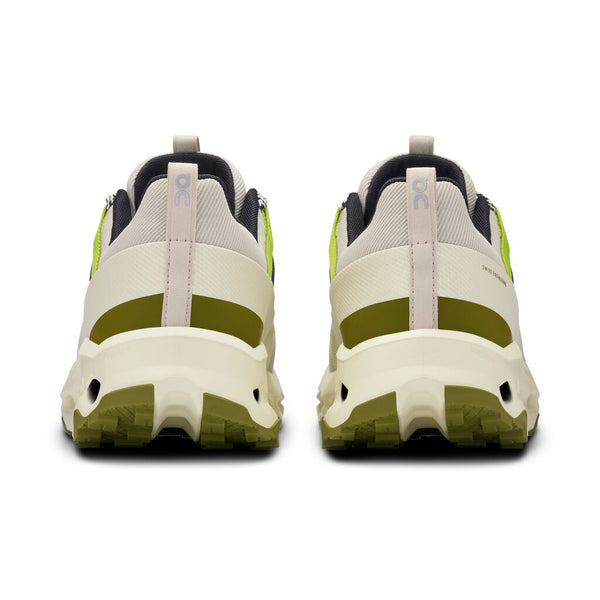 Back view of a pair of beige and green sneakers on a white background.