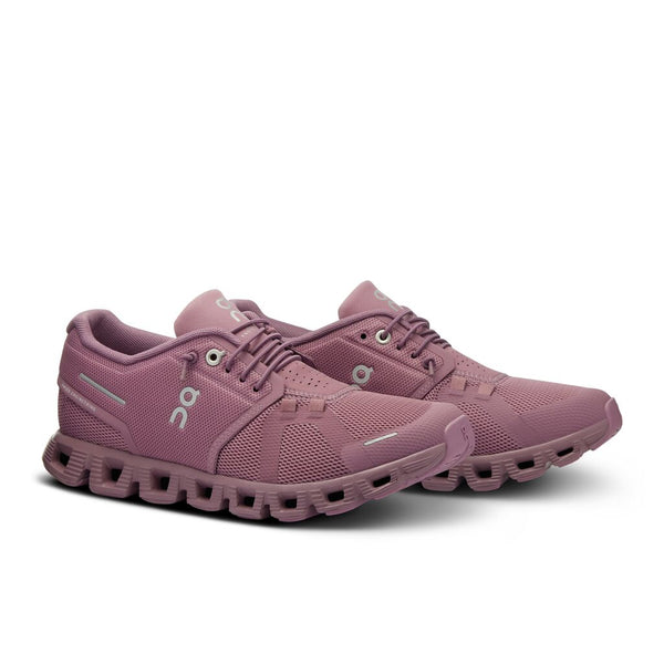Pair of pink running shoes on a white background that are called Fig color.