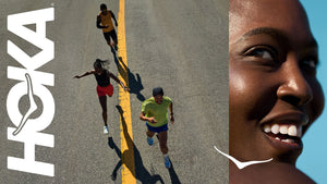 A banner image for the brand HOKA containing a white HOKA logo on the far left, an overhead view of three runners running down the middle yellow line of a road in the middle and an up-close view of a female's face smiling to the far right.