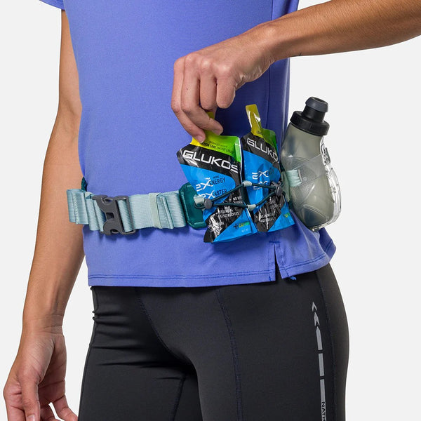 Person wearing a running belt with GLUKOS energy gels and a water bottle on a plain background