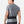 Person wearing a gray athletic shirt and black pants with a black belt on a white background