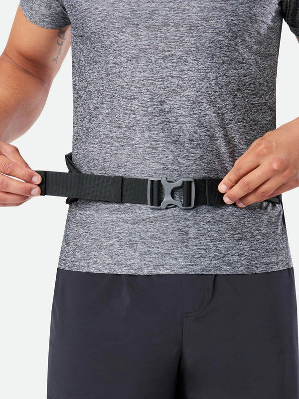 Person adjusting a black belt around their waist on a plain background