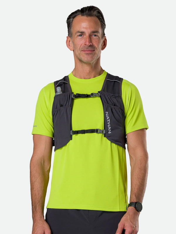 Man wearing a green shirt and black Nathan running vest on a white background