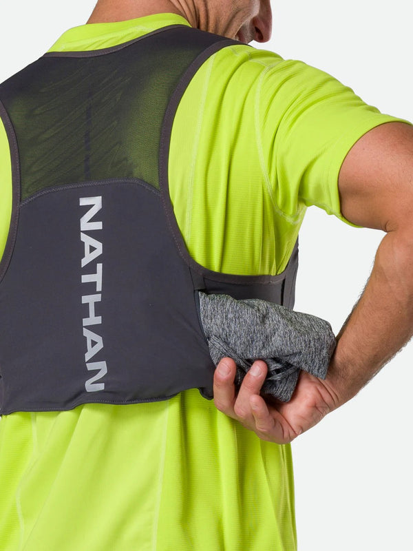 Person wearing a Nathan hydration vest and holding a gray towel.