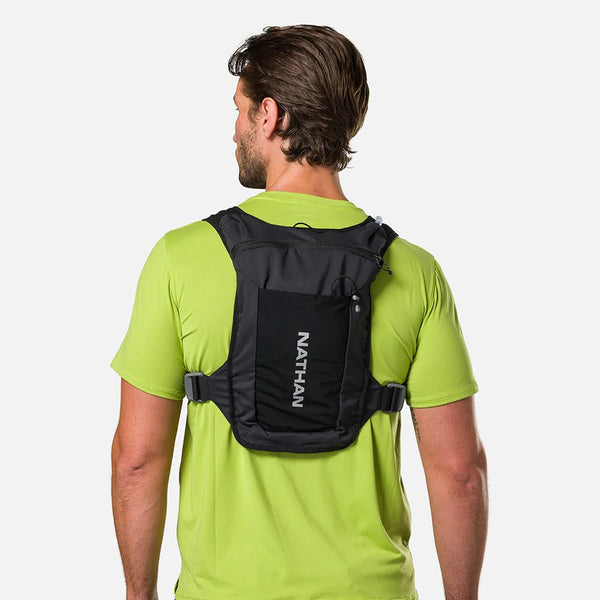 Person wearing a black Nathan hydration backpack on a white background