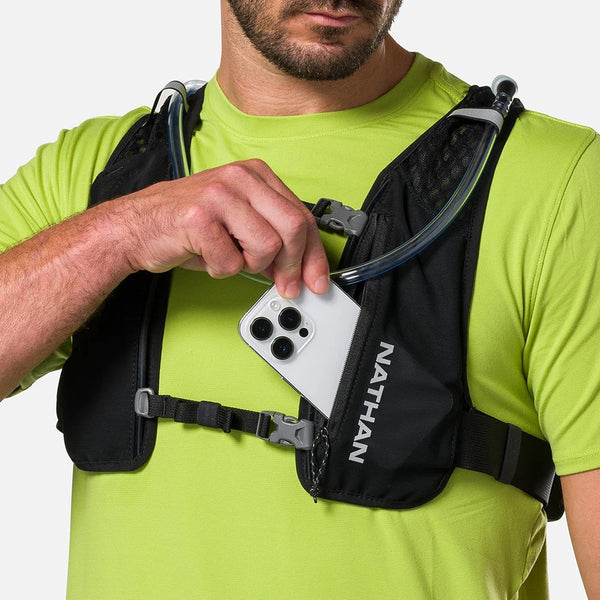 Person wearing a Nathan hydration vest holding a smartphone.
