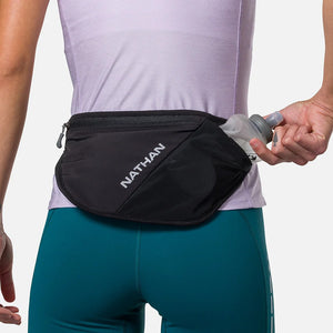 Person wearing a black waist bag with 'Nathan' branding, holding a water bottle.