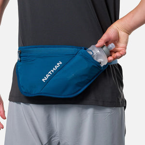 Person wearing a blue waist pack with 'Nathan' branding, holding a water bottle.