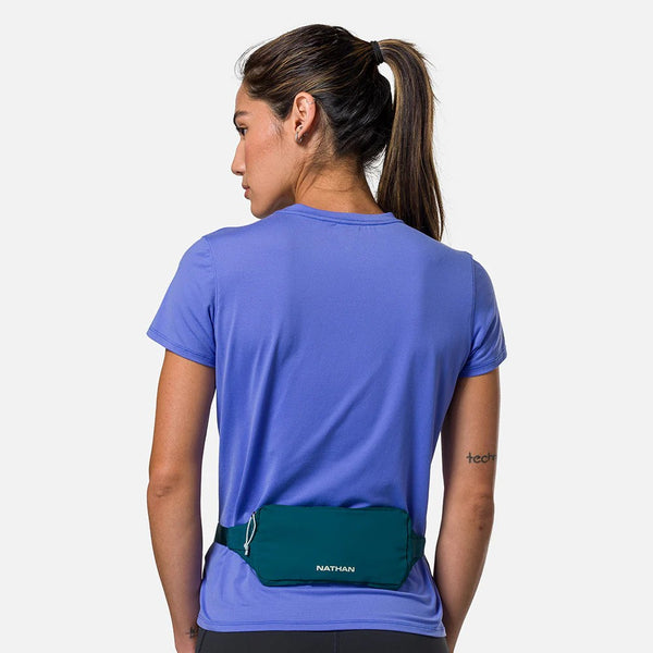 Person wearing a blue shirt with a green waist bag on a white background