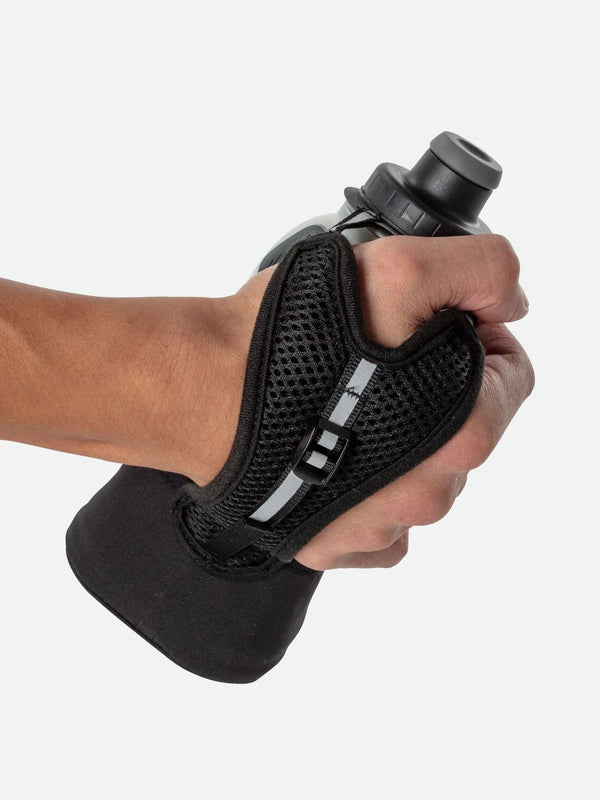 Hand holding a black water bottle with a wrist strap against a white background