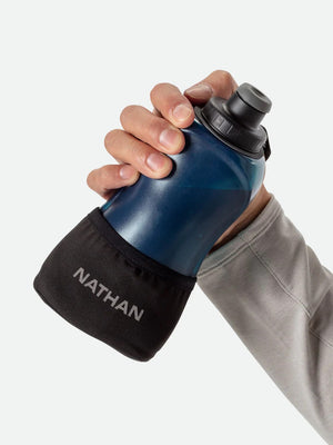 Hand holding a blue and black Nathan sports bottle against a white background