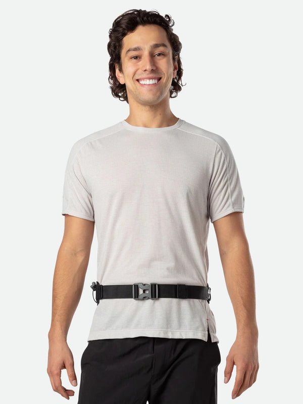 Man wearing a light gray t-shirt and black pants with a belt on a white background