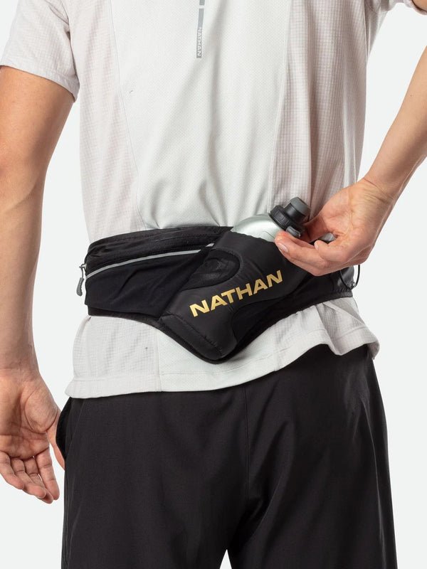 Person wearing a black waist bag with 'Nathan' branding on a white background