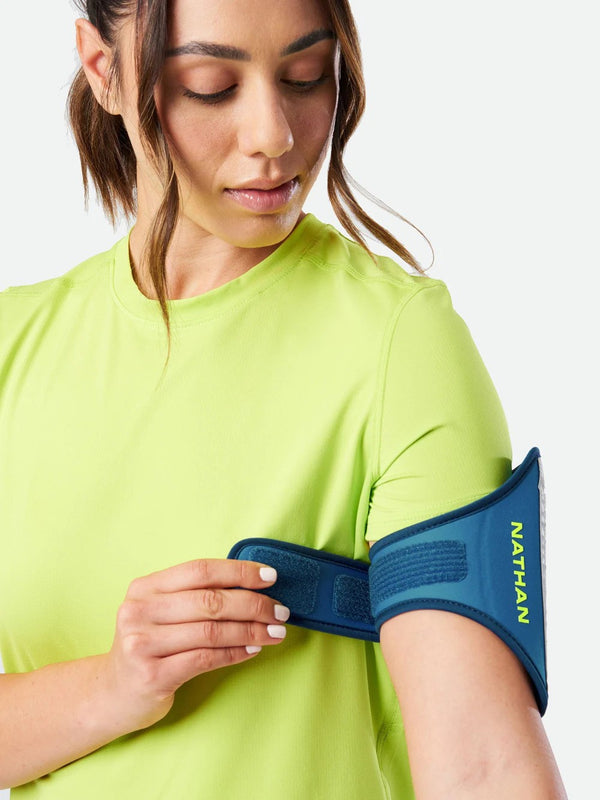 Woman wearing a blue Nathan sports arm band on a white background