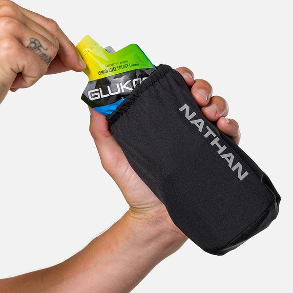 Hand holding a Nathan energy gel pouch with a Glukosan sports drink mix packet.