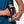 Person holding a water bottle with a black holder against a blue shirt background