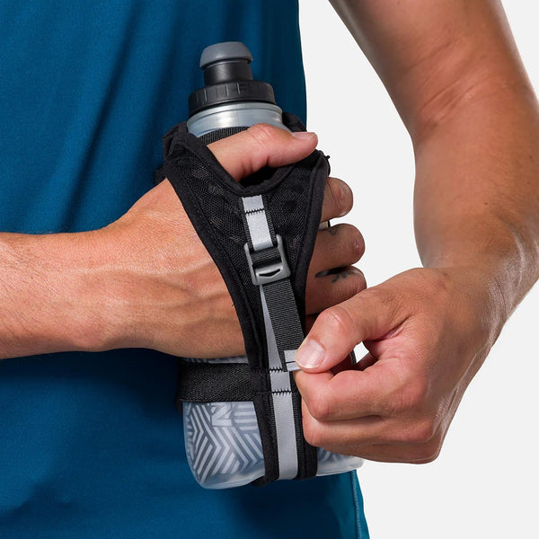 Person holding a water bottle with a black holder against a blue shirt background