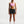 Woman wearing a pink sports bra and black shorts on a white background