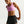 Woman wearing a pink sports bra and black shorts with Nike logo on a white background
