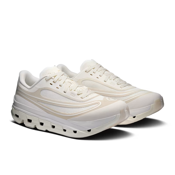 A pair of low-top athletic sneakers in a monochromatic cream and beige colorway, featuring a chunky sculpted sole with air-like cutouts, shown against a plain white background.