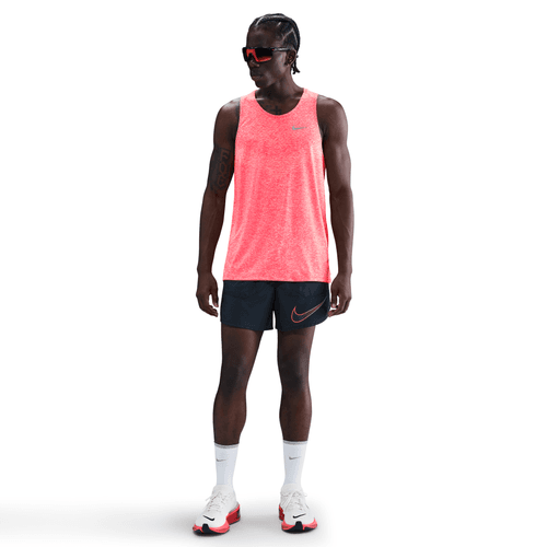 Person wearing a bright red tank top and black shorts with Nike logo on a white background