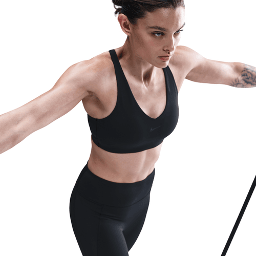 Woman wearing a black sports bra and leggings on a white background