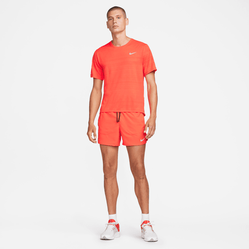Man wearing a bright orange Nike outfit on a white background