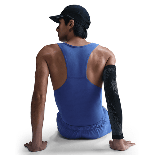 Person wearing a blue tank top and black arm sleeve sitting on a white background