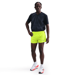 Person wearing a black shirt and bright yellow shorts with a Nike logo on a white background