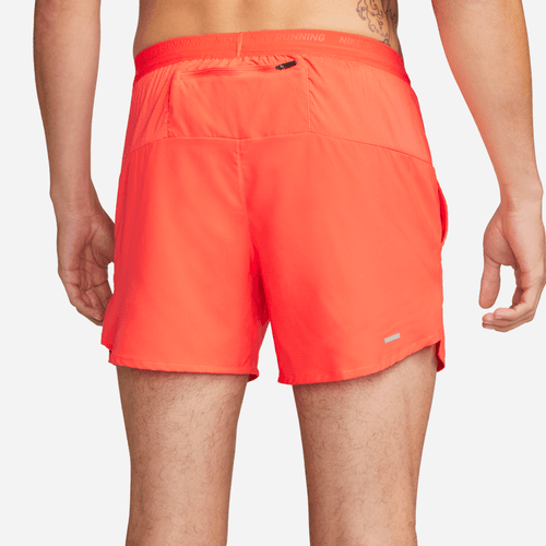 Orange athletic shorts worn by a person on a white background