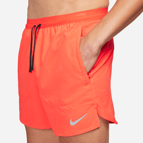 Orange running shorts with a Nike logo and pockets on a white background