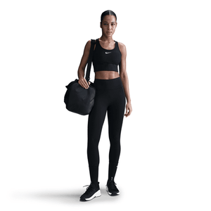 Woman in black athletic wear holding a black duffel bag on a white background