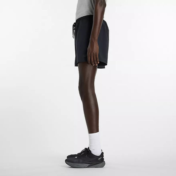 Person wearing black athletic shorts and black sneakers on a white background