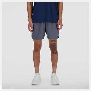 Person wearing navy tank top and gray shorts on a white background