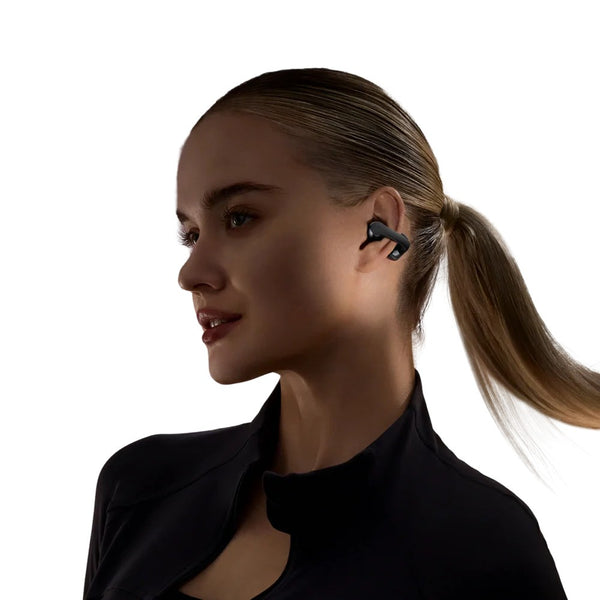 Woman wearing a black earbud with a plain background