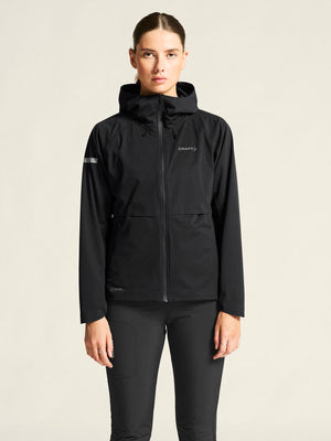 Person wearing a black jacket with a brand logo on a beige background