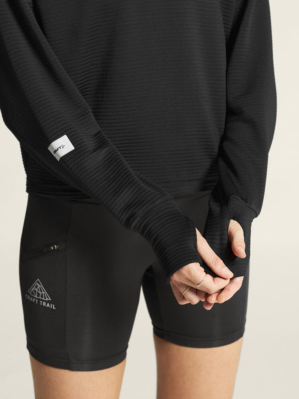 Person wearing black athletic outfit with visible brand logos on a neutral background