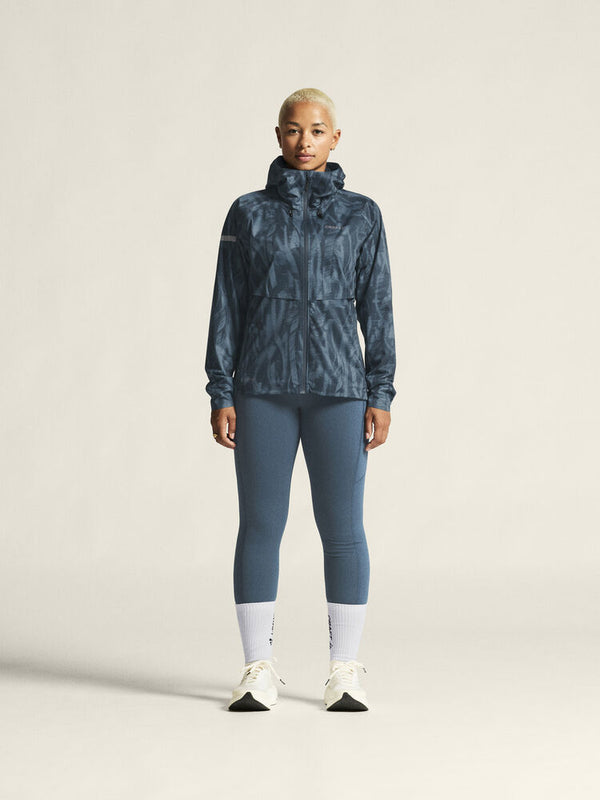 Person wearing a blue patterned jacket and leggings on a plain background