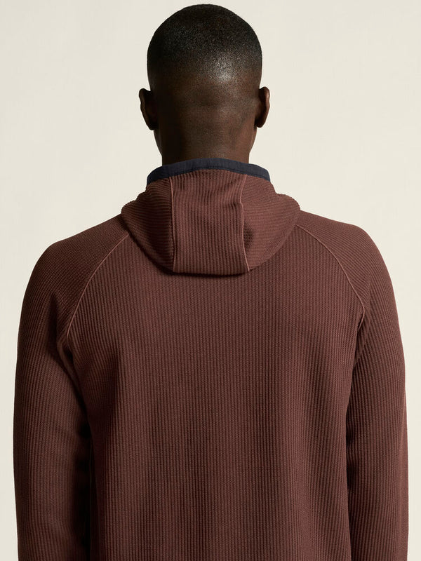 Person wearing a brown ribbed sweater against a beige background