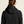 Person wearing a black jacket with a hood on a beige background