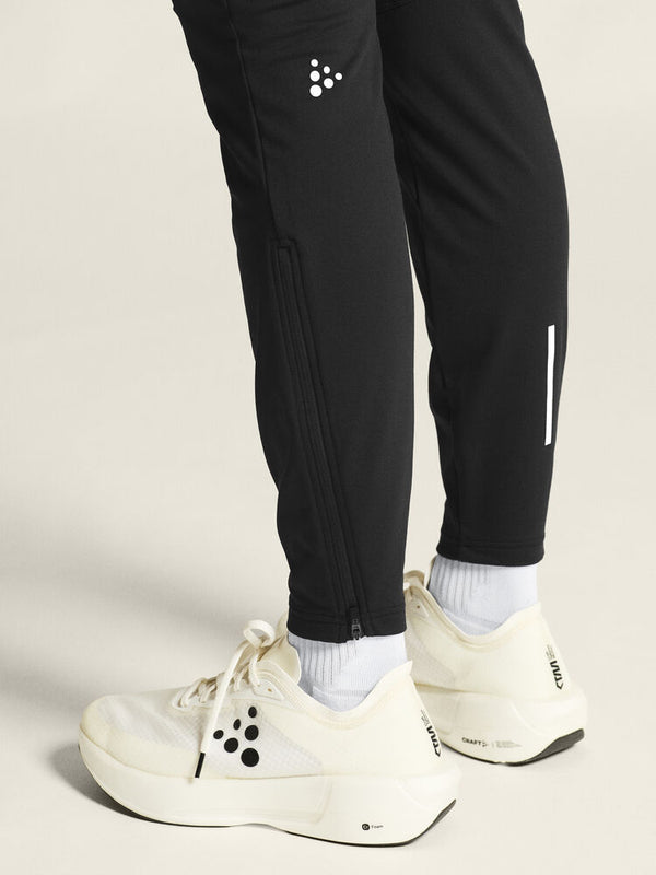 Black jogger pants with white sneakers on a neutral background