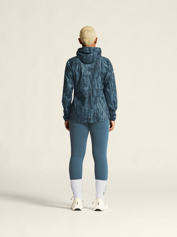 Person wearing a blue patterned jacket and leggings on a beige background