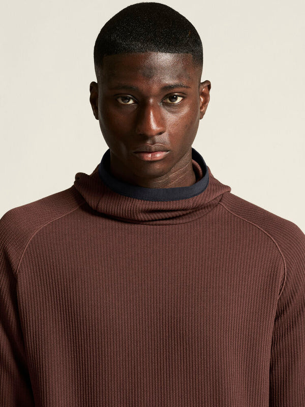 Man wearing a brown ribbed sweater against a beige background