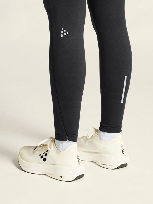 Black leggings with a brand logo worn by a person, paired with white running shoes on a light background.
